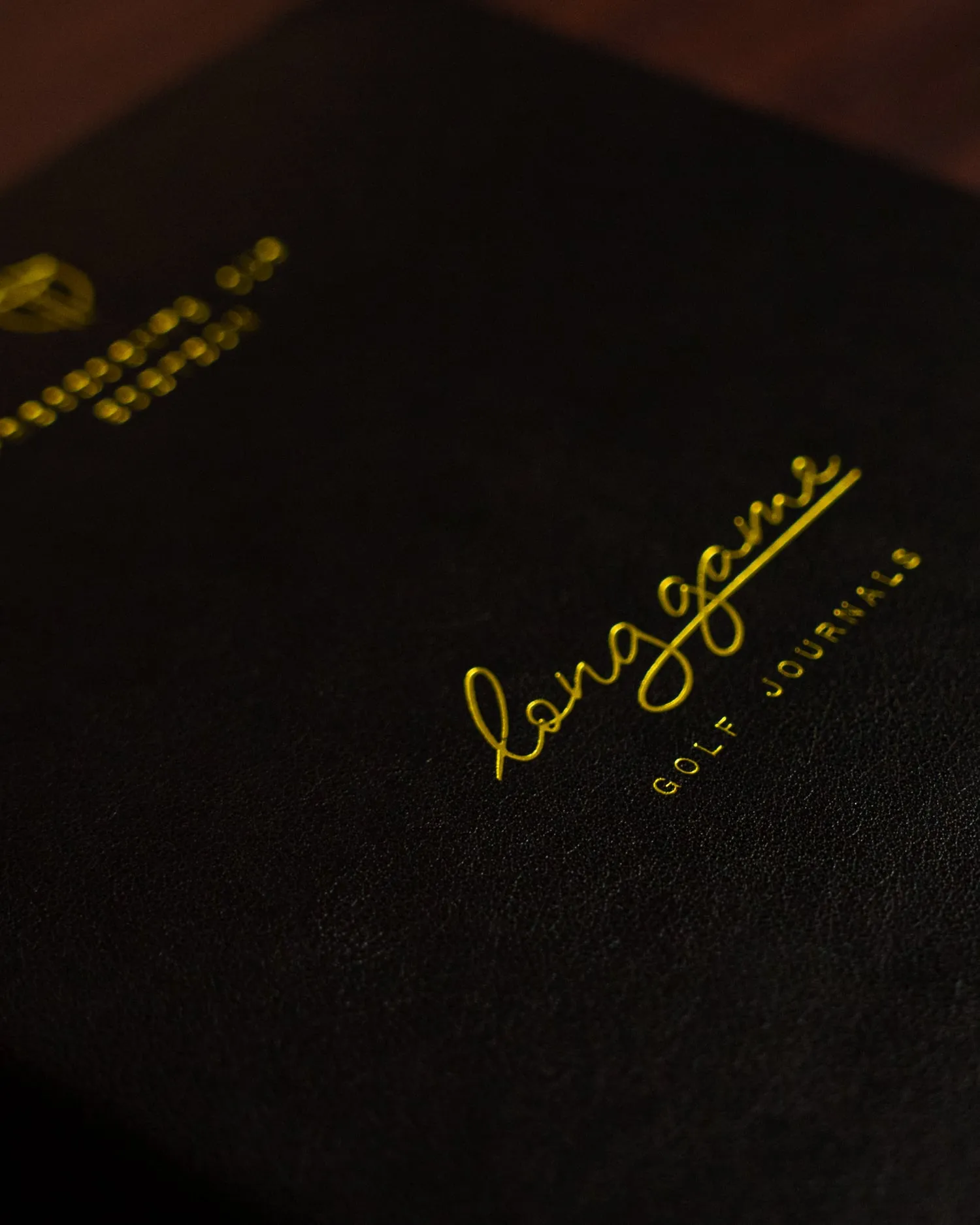 The journal made for the International Team, black cover with the crest and the Long Game mark in gold foil
